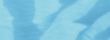 Bulanık, ince parlak detayları olan, derinlik ve doku oluşturmak için özenle katlanmış, yumuşak mavi bir kumaş. Işık maddenin hassas dokusunu vurguluyor..