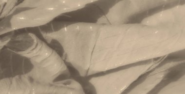 Bulanık yumuşak bej kumaş dokusu, zarif parlak çizgileri, kıvrımları var. Yumuşak ışık, kumaş yüzeyine ince bir şekilde yansıyarak, huzurlu ve havadar bir his yaratır..