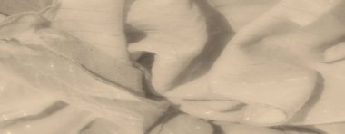 Yumuşak, parlak çizgileri olan bulanık bej kumaş nazikçe kıvrılır. Tekstil 'in pürüzsüz yüzeyi ve ince ışık yansımaları hafif bir zarafet ve cazibe yaratır..