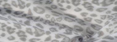 Görüntü, bu hassas kumaş, organik ve soyut gri şekillerle süslenmiş yumuşak beyaz maddenin akış şeklini ortaya çıkarıyor. Kumaşın hareketi ve dokusu yumuşak ve havadar bir kalite iletir..