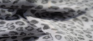 Işığın bulanık görüntüsü, narin gri leopar desenli havadar kumaş beyaz bir zeminde. Yumuşak kıvrımlar ve dokular iç mekanlar ve moda için uygun sakin, zarif bir estetik yaratıyor..