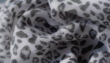 Bulanık beyaz leopar desenini açık renk arka planda yakalar, şık, minimalist tekstil görünümü için ince bir kontrastı vurgular..