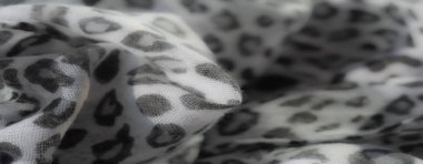 Gri leopar lekeleriyle bezenmiş beyaz kumaş üzerinde bulanık bir etki. Yumuşak, organik bir his katıyor. Tekstil geçmişi için ideal olan yakın çekim, dokulu bir yüzeyi ortaya çıkarıyor..