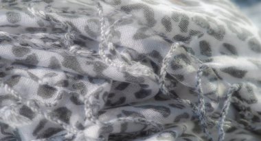 Bulanık beyaz leopar desenini açık renk arka planda yakalar, şık, minimalist tekstil görünümü için ince bir kontrastı vurgular..