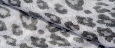 Hayvan izi motifli beyaz ve gri desenli bir kumaşın bulanık görüntüsü. Yumuşak kıvrımlar ve detaylı dokuma zarif, modern bir stil hissi veriyor..