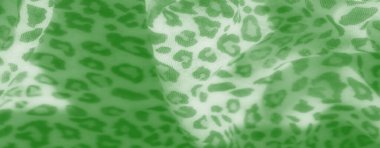 Yeşil kumaş, yumuşak kıvrımlarla zarifçe akan hayvan işaretlerini anımsatıyor. Tekstil yüzeyi karmaşık dokuları ve doğal renkleri vurgular..