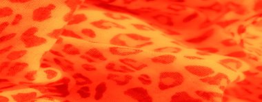 Ayırt edici leopar desenli sarı ve turuncu kumaşın bulanık görüntüsü. Yumuşak, dalgalı kıvrımlar kumaşa sıcak, davetkar bir görünüm verir..