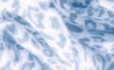 Mavi tonlu leopar desenli kumaşın ince dokuya yakın görüntüsü. Yumuşak bulanık, bu tekstil görüntüsü hayvanlardan esinlenilmiş tasarımın sakin ve narin modelini yakalar..