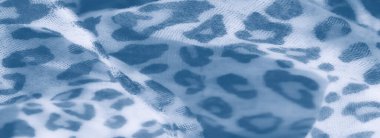 Görüntü: Leopar desenli mavi ve beyaz kumaşın sanatsal yakın çekimi, bulanık bir efektle yavaşça katlanmış, tekstil yüzeyinde modern ve sakin bir görünüm yaratıyor.
