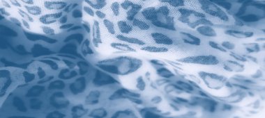 İnce leopar desenli mavi renkli kumaşın yakın plan görüntüsü. Yumuşak kıvrımlar, tekstil boyunca soyut bir dokunuşla sakin bir estetik yaratıyor..