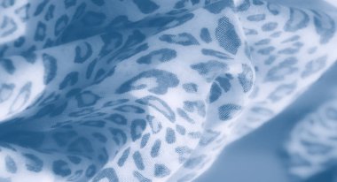 Görüntü. Yumuşak, bulanık leopar desenli mavi renkli kumaş sükunet hissi yayar. Yakından bakınca nazikçe kıvrılıyor, davetkar ve rahatlatıcı bir doku yaratıyor..