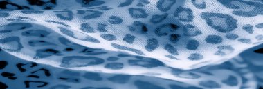 Mavi ve beyaz kumaş üzerinde leopar benzeri lekeleri olan bulanık bir etki. Yumuşak odak hassas dokuları ve akışkan kıvrımları vurgular, tasarıma derinlik katar.