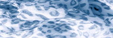 Yumuşak bir kumaş üzerine bulanık bir etki ve sessiz mavi tonlarda leopar benzeri soyut bir desen. Kumaşın hafif dokusu ve akan kıvrımları onun narin dokusunu güçlendirir.