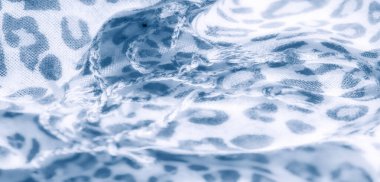 Görüntü, beyaz kumaş üzerinde leopar benzeri yumuşak mavi izler sergiliyor. Hassas ve akıcı dokuyu vurguluyor. Arkaplan ya da kumaş tasarımı için mükemmel.