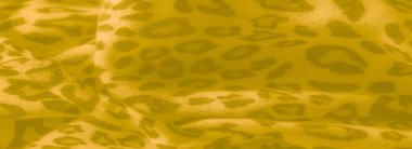 İnce leopar esinlenilmiş desenleri ve pürüzsüz kıvrımları olan sarı kumaş, sıcak ama karmaşık bir estetik yaratıyor.