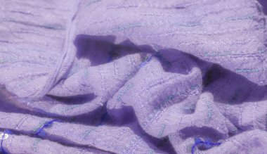 Lavanta desenli kumaş bulanıklığı, dikişli detaylar ve pullu aksanlar, zarif bir ışık oyunu yaratıyor. Mavi iplik derinlik ve ilgi katıyor..