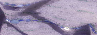 Pırıl pırıl pulları ve desenli dikişleri olan mor kumaşın bulanık görüntüsü yumuşak eflatun tonları ve yeşil nakışlı detaylarıyla lüks bir görünüm sunuyor.