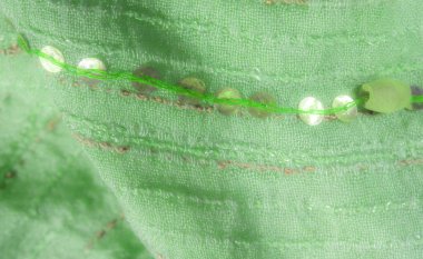 Bulanık, altın iplikli yeşil kumaş ve bir sıra pulla zarif bir denge sergiliyor ve lüks dekor ve moda için ideal yumuşak, karmaşık bir dokuda parıldıyor..