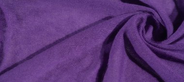 Görüntü, canlı mor bir kumaş, karmaşık bir şekilde katlanmış ve dokulu, zengin, rahat bir dokuyu ortaya çıkarıyor. Yumuşak kıvrımlar, tekstil ve moda tasarımları için ideal derinlik ve zarafet yaratır..