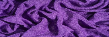 Görüntü, canlı mor bir kumaş, karmaşık bir şekilde katlanmış ve dokulu, zengin, rahat bir dokuyu ortaya çıkarıyor. Yumuşak kıvrımlar, tekstil ve moda tasarımları için ideal derinlik ve zarafet yaratır..