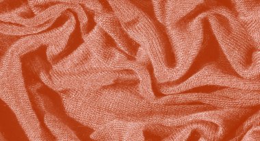 Görüntü, yumuşak, hassas kıvrımlı turuncu bir kumaş sunuyor. Karmaşık desenler ve gölgeler yaratıyor. Kumaşın pürüzsüz ve pürüzsüz bir görünümü var.