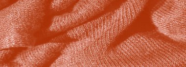 Görüntü, yumuşak, hassas kıvrımlı turuncu bir kumaş sunuyor. Karmaşık desenler ve gölgeler yaratıyor. Kumaşın pürüzsüz ve pürüzsüz bir görünümü var.