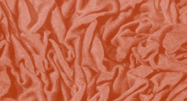 Görüntü, yumuşak, hassas kıvrımlı turuncu bir kumaş sunuyor. Karmaşık desenler ve gölgeler yaratıyor. Kumaşın pürüzsüz ve pürüzsüz bir görünümü var.