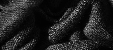 Bulanık, yumuşak, akışkan kıvrımlar halinde düzenlenmiş koyu kumaşın karmaşık dokusunu yakalar. Bu gri pullu kumaş derinlik ve dokunsal bir his yayar ve pürüzsüz, dokunmuş detaylarına daha yakından bakmamızı sağlar..