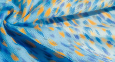 Renkli mavi kumaş, dağınık sarı ve açık mor desenli. Dekoratif, moda ve sanatsal uygulamalara uygun canlı bir görünüm veriyor..