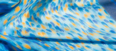 Bulanık etkisi bu mavi ve turuncu desenli kumaşın pürüzsüz kıvrımlarını arttırır, organik şekiller uyum içinde harmanlanır. Yumuşak dokusu olan canlı bir tekstil..