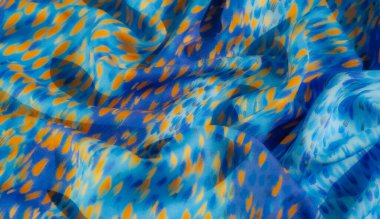 Parlak sarı ve ince mor lekeli mavi bir kumaşın bulanık yakın plan görüntüsü kumaşa dağılmış renk darbelerine benziyor. Yumuşak kıvrımlar dokunsal bir kalite sağlar.,