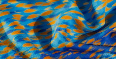 Turuncu ve mor aksanlı canlı mavi kumaş, dinamik bir renk karışımı oluşturuyor. Akan katlar ve soyut tasarım bir hareket ve derinlik hissi getirir.,