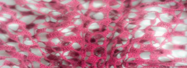 Beyaz bir zemin üzerinde açık pembe dantel kumaş bulanıklığı, yumuşak bir şekilde akan karmaşık bir ağ deseni sergiliyor, narin bir dokuyla zarif ve havadar bir görünüm yaratıyor..