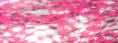 Hassas, açık ağ desenli pembe dantel kumaş üzerinde bulanık bir etki. Yumuşak dokular ve havadar görünüş yumuşak ışıklandırmayla geliştirilmiş romantik bir estetik yaratıyor..