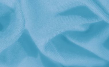 Derin su tonlu kumaşın bulanık görüntüsü, yumuşak kırışıklıkları ve kıvrımları sıvı ve dalgalı bir görünümle gösteriyor, tekstil kültüründe bir hareket ve incelik hissi uyandırıyor..