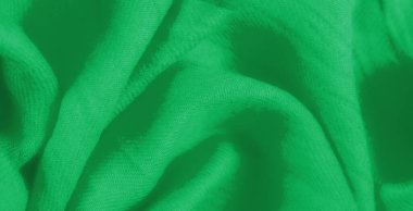 Katmanlı kareli desenli Bulanık Yeşil kumaş dokunmuş yapısını vurguluyor ve kumaşların üzerindeki ışık ve gölge karışımından derinlik ekliyor.