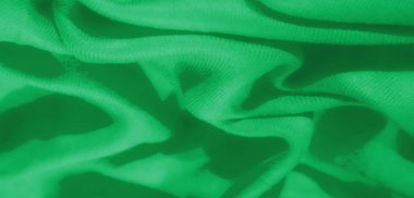 Katmanlı kareli desenli Bulanık Yeşil kumaş dokunmuş yapısını vurguluyor ve kumaşların üzerindeki ışık ve gölge karışımından derinlik ekliyor.