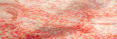 Yumuşak turuncu ve pembe desenli hafif kumaşın ayrıntılı görüntüsü, maddenin havadar ve hassas kalitesini vurguluyor. İnce kıvrımlar ve nazik kıvrımlar zariflik katar.