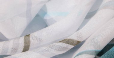 Beyaz arka planda mavi ve bej desenli yumuşak, havadar kumaş bulanıklığı bir sıvı ve açık estetik oluşturur. Yumuşak kıvrımlar dokunun yumuşaklığını arttırır.