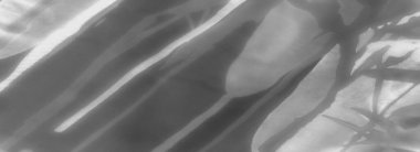 Koyu ve açık tonların bir karışımını gösteren tek renkli bir kumaş görüntüsü. Kumaş, belli belirsiz gölge desenleriyle zarifçe katlanır ve kompozisyona derinlik ve görsel doku ekler.