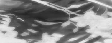 Görüntü, ışık ve gölgelerin yüzeyde oynadığı, ince dokuları ve tonsal varyasyonları vurguladığı gri ölçekte kumaşın soyut bir görünümünü yakalıyor..