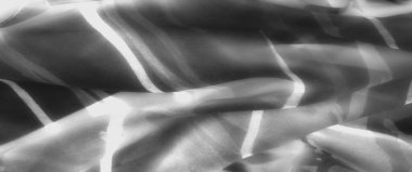 Bulanık, koyu ve açık renkli kumaş üzerinde karmaşık bir oyun, pürüzsüz ama katmanlı bir görünüm yaratıyor. Kumaş, ince detaylarla sürekli bir dalga gibi görünür..