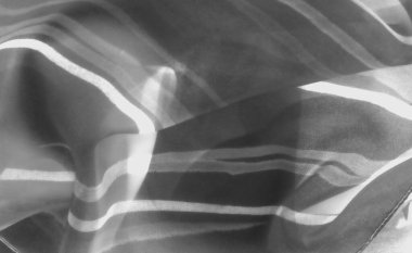 Saf kumaş katmanlarında ışık kırılması bulanıklığı, monokromda soyut desenler yaratıyor. Bileşim, gri tondaki yumuşaklık ve tonsal çeşitliliği vurgular