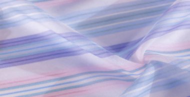 Yumuşak, havadar bir kompozisyonda ince mavi, lavanta ve pembe çizgili bulanık kumaş. Saf doku ve akış çizgileri zarif ve rahatlatıcı bir görsel etki yaratır..