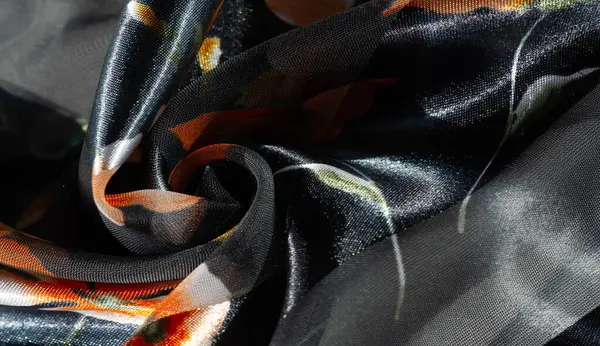 Bulanık, yumuşak ışık bu çiçekli kumaşın dokusunu ve parıltısını gözler önüne seriyor. Siyah ve gri çizgilere karşı portakal çiçekleri seriliyor zarafetle zarafet ve lüks saçmak için örtülüyor..