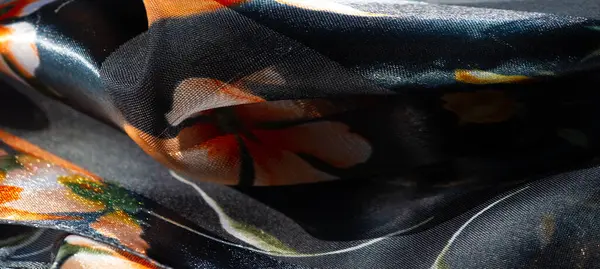 Yumuşak, pürüzsüz kumaştan oluşan bulanık, parlak turuncu ve sarı çiçek aksanlı koyu mavi bir arkaplan. Parlak parıltı onun lüks ve zarif görünümünü arttırır..