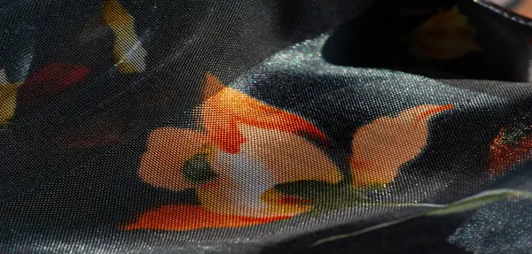 Koyu mavi bir tabanda turuncu ve sarı çiçek izleriyle parıldayan saf kumaş bulanıklığı. Kumaşlar parlak ve narin katlar ince, yumuşak bir estetiği çağrıştırıyor. .