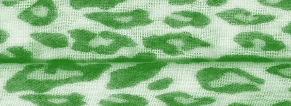 Canlı yeşil bir kumaşın bulanıklığı ve hayvanlardan esinlenilmiş desenler katlanmış yüzeyinde dinamik bir doku oluşturuyor. Kumaşlar narin dokumayı vurguluyor, arka plan için ideal..