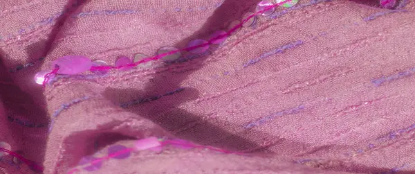 Pembe pullar ve lavanta dikişleriyle süslenmiş açık pembe kumaşın bulanık görüntüsü. Yumuşak dokusu ve ince parıltısı zarif ve lüks bir görünüm yaratır..