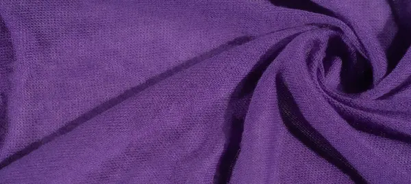 Görüntü, canlı mor bir kumaş, karmaşık bir şekilde katlanmış ve dokulu, zengin, rahat bir dokuyu ortaya çıkarıyor. Yumuşak kıvrımlar, tekstil ve moda tasarımları için ideal derinlik ve zarafet yaratır..